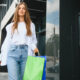 mulher com sacola de compras em frente a uma loja